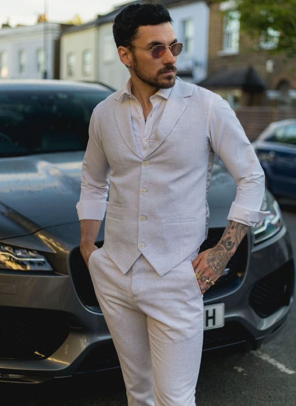 Embrace effortless summer sophistication with this grey 2-piece linen suit, designed with comfort and style in mind. Featuring a coordinating waistcoat and trousers, this ensemble is ideal for warm-weather occasions. The lightweight and breathable linen blend keeps you cool and comfortable, even on the hottest days. With its relaxed yet refined appearance, this suit strikes the perfect balance between smart and casual—ideal for garden parties, destination weddings, or daytime events. Whether dressed up with a crisp shirt or styled casually with loafers, this suit adapts easily to your look and lifestyle.\n2-piece set includes waistcoat and trousers in a light grey tone\nLightweight and breathable fabric perfect for summer events\nRelaxed yet stylish look, ideal for casual weddings or garden parties\nVersatile styling—elevate with formalwear or dress down for smart-casual looks\nMaterial: 80% Cotton, 20% Acrylic