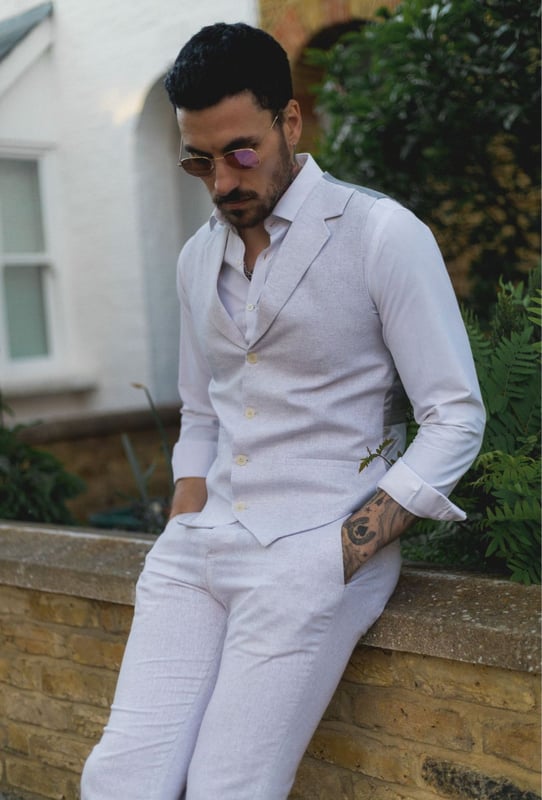 Embrace effortless summer sophistication with this grey 2-piece linen suit, designed with comfort and style in mind. Featuring a coordinating waistcoat and trousers, this ensemble is ideal for warm-weather occasions. The lightweight and breathable linen blend keeps you cool and comfortable, even on the hottest days. With its relaxed yet refined appearance, this suit strikes the perfect balance between smart and casual—ideal for garden parties, destination weddings, or daytime events. Whether dressed up with a crisp shirt or styled casually with loafers, this suit adapts easily to your look and lifestyle.\n2-piece set includes waistcoat and trousers in a light grey tone\nLightweight and breathable fabric perfect for summer events\nRelaxed yet stylish look, ideal for casual weddings or garden parties\nVersatile styling—elevate with formalwear or dress down for smart-casual looks\nMaterial: 80% Cotton, 20% Acrylic