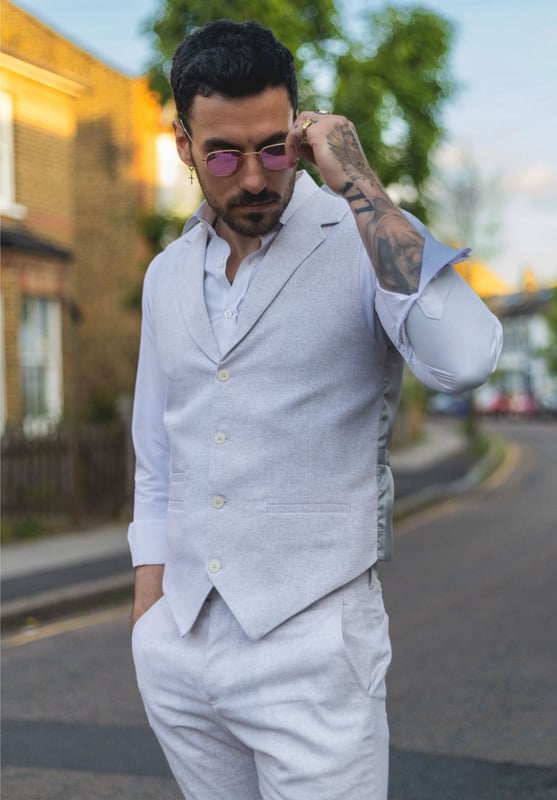 Embrace effortless summer sophistication with this grey 2-piece linen suit, designed with comfort and style in mind. Featuring a coordinating waistcoat and trousers, this ensemble is ideal for warm-weather occasions. The lightweight and breathable linen blend keeps you cool and comfortable, even on the hottest days. With its relaxed yet refined appearance, this suit strikes the perfect balance between smart and casual—ideal for garden parties, destination weddings, or daytime events. Whether dressed up with a crisp shirt or styled casually with loafers, this suit adapts easily to your look and lifestyle.\n2-piece set includes waistcoat and trousers in a light grey tone\nLightweight and breathable fabric perfect for summer events\nRelaxed yet stylish look, ideal for casual weddings or garden parties\nVersatile styling—elevate with formalwear or dress down for smart-casual looks\nMaterial: 80% Cotton, 20% Acrylic