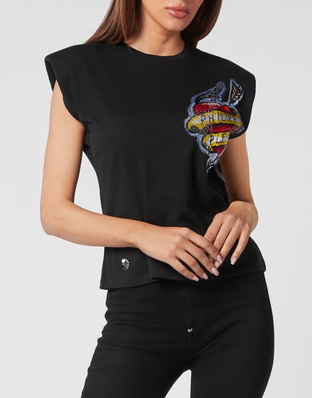 Esta camiseta de tirantes con hombreras combina el arte de los tatuajes vintage con una estructura atrevida, perfecta para combinar con vaqueros de cintura alta o con cuero para lucir un estilo seguro y a la última.   Los hombros acolchados esculpen una silueta poderosa y moderna.   El gráfico inspirado en los tatuajes aporta un encanto rebelde con detalles vibrantes   El tejido de algodón puro ofrece suavidad y comodidad transpirable   Los adornos de fibra de vidrio añaden un brillo sutil y un acabado de lujo   Una pieza destacada para looks de día a noche con actitud