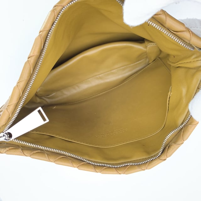 VINTAGE, RRP AS NEW
Bottega Veneta Intrecciato Zip Pouch - A Touch of Woven Gold  There's something unmistakably timeless about Bottega Veneta's craftsmanship-and this Intrecciato Zip Pouch Wristlet is no exception. Woven from buttery-soft lambskin leather in a luminous gold tan, it captures the quiet luxury the house is celebrated for. Compact yet refined, it's the kind of piece that slips effortlessly from day to night, always adding a touch of artisanal elegance.  Secured with a zip closure and adorned with silver-tone hardware, the exterior is a work of woven art, while the matching lambskin-lined interior offers a simple open compartment and a single patch pocket for essentials. Discreetly stamped with 'Bottega Veneta - Made in Italy' and its original ity label, this clutch is more than a bag-it's a moment of Italian design history you can hold in your hand.  Perfect for collectors, minimalists, and lovers of enduring beauty in small forms. Condition Rating: B - VERY GOOD CONDITIONCondition Details: Some darkness on leather along the opening, on a side. A couple of pen marks internally. Please check the photos carefully and ask if you need to know more details or if you have any doubts.Measurements (cm):Depth: 5.1Height: 17.8Length: 27.9Other Details: Dustbag? NoKeys? NoBox? No Measurments:  width: 51 mm length: 279 mm height: 178 mm