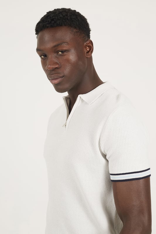 Elevate your smart-casual style with this polo from Brave Soul, designed with a sleek concealed 1/4 zip neck fastening for a clean, contemporary finish. Made from an all-over rib knit fabric, this polo offers a comfortable stretch fit with refined texture. Contrast stripe trims at the collar and cuffs add a pop of detail, to this elevated everyday essential. Model wears UK size M.