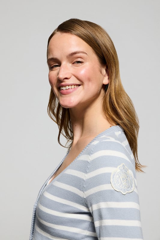 Die Damenstrickjacke Cordelia ist ein maritim inspiriertes Stück, das Eleganz und Funktionalität vereint. Sie ist aus Baumwolle und Polyamid gefertigt und hat eine schmale Passform mit V-Ausschnitt, die eine schlanke Silhouette schafft. Der Knopfverschluss mit farblich abgestimmten Logoknöpfen sorgt für ein raffiniertes Finish, während die Rippbündchen an den Ärmeln und am Bund für einen bequemen Sitz sorgen. Das farblich abgestimmte Nahtband am Kragen mit Polo Club Logo unterstreicht die Eleganz dieses Modells. Das kontrastierende Streifendesign und das einfarbige gestickte Wappen auf dem Ärmel sind ikonische Details unserer maritimen Kollektion.