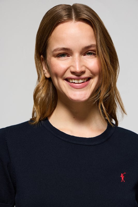 Dieser kurzärmlige Damenstrickpullover ist die perfekte Kombination aus Eleganz und Komfort. Er ist aus weicher Baumwolle gefertigt und hat eine reguläre Passform, die sich sanft an die Silhouette anschmiegt. Der Rundhalsausschnitt und die gerippten Abschlüsse an den Ärmeln, am Kragen und am Bund sorgen für einen bequemen Sitz. Das marineblaue Nahtband am Kragen mit Polo Club Logo unterstreicht die Eleganz dieses Modells. Das emblematische Rigby Go Logo in Kontrastfarbe auf der Brust unterstreicht seine einzigartige Optik. Ideal allein getragen der in Kombination mit unserer geknöpften Strickjacke.