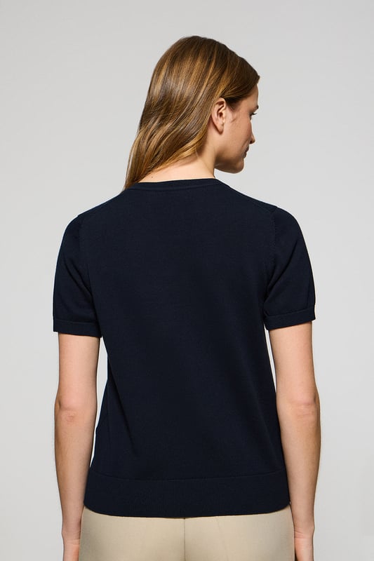Dieser kurzärmlige Damenstrickpullover ist die perfekte Kombination aus Eleganz und Komfort. Er ist aus weicher Baumwolle gefertigt und hat eine reguläre Passform, die sich sanft an die Silhouette anschmiegt. Der Rundhalsausschnitt und die gerippten Abschlüsse an den Ärmeln, am Kragen und am Bund sorgen für einen bequemen Sitz. Das marineblaue Nahtband am Kragen mit Polo Club Logo unterstreicht die Eleganz dieses Modells. Das emblematische Rigby Go Logo in Kontrastfarbe auf der Brust unterstreicht seine einzigartige Optik. Ideal allein getragen der in Kombination mit unserer geknöpften Strickjacke.