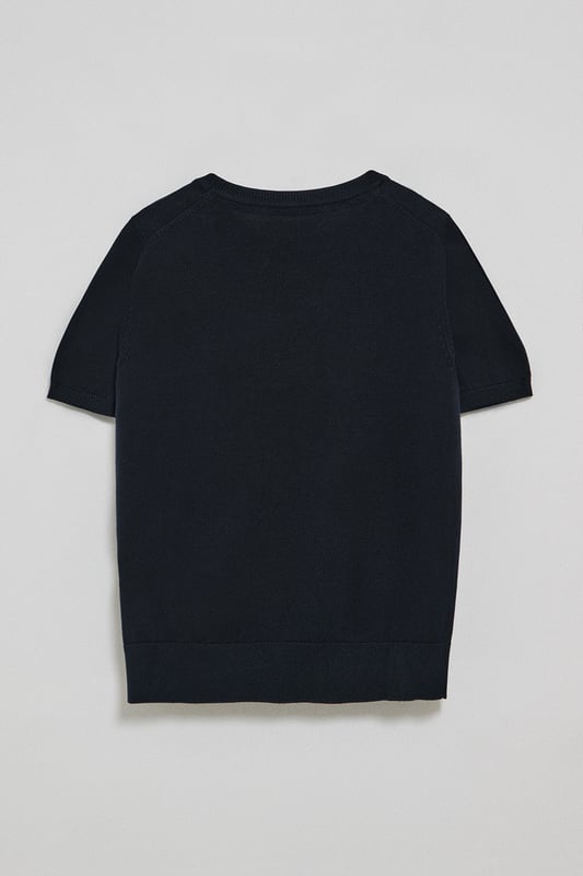 Dieser kurzärmlige Damenstrickpullover ist die perfekte Kombination aus Eleganz und Komfort. Er ist aus weicher Baumwolle gefertigt und hat eine reguläre Passform, die sich sanft an die Silhouette anschmiegt. Der Rundhalsausschnitt und die gerippten Abschlüsse an den Ärmeln, am Kragen und am Bund sorgen für einen bequemen Sitz. Das marineblaue Nahtband am Kragen mit Polo Club Logo unterstreicht die Eleganz dieses Modells. Das emblematische Rigby Go Logo in Kontrastfarbe auf der Brust unterstreicht seine einzigartige Optik. Ideal allein getragen der in Kombination mit unserer geknöpften Strickjacke.