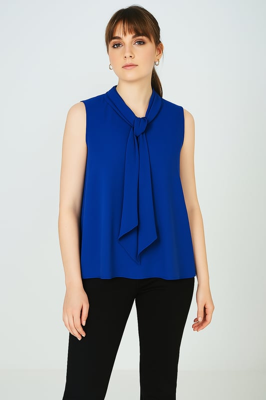 Voeg een vleugje elegantie toe aan je garderobe met deze mouwloze blouse in levendig kobaltblauw. Het is gemaakt van 100% lichtgewicht polyestervoile en valt zacht en luchtig, waardoor het de hele dag comfortabel aanvoelt. Het opvallende detail is de sierlijke halslijn met strikje, die vrouwelijke charme en veelzijdigheid aan je look toevoegt. Draag hem met een pantalon of een rok voor een verzorgde kantooroutfit, of combineer hem met een jeans voor een chique weekendsfeer.