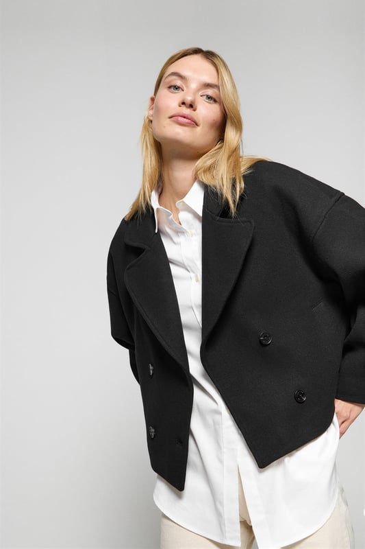 Der Damen-Kurzmantel Lona ist ideal, um jeden Look zu vervollständigen. Er verbindet Stil und Komfort auf perfekte Weise. Er ist aus einem Woll- und Polyestermischgewebe gefertigt. Das größere Revers mit Einschnitt und der Vierknopfverschluss mit Logoprägung verleihen ihm eine klassische, elegante Note. Mit zwei Vordertaschen und einer dezenten Innentasche ist er praktisch und funktionell. Das Polo Club Logo auf der Passe verleiht ihm einen exklusiven Touch. Ein ideales Kleidungsstück für die Übergangszeit oder für kühlere Tage.