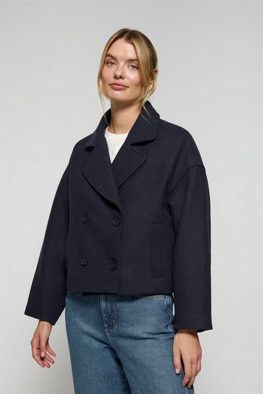 Der Damen-Kurzmantel Lona ist ideal, um jeden Look zu vervollständigen. Er verbindet Stil und Komfort auf perfekte Weise. Er ist aus einem Woll- und Polyestermischgewebe gefertigt. Das größere Revers mit Einschnitt und der Vierknopfverschluss mit Logoprägung verleihen ihm eine klassische, elegante Note. Mit zwei Vordertaschen und einer dezenten Innentasche ist er praktisch und funktionell. Das Polo Club Logo auf der Passe verleiht ihm einen exklusiven Touch. Ein ideales Kleidungsstück für die Übergangszeit oder für kühlere Tage.