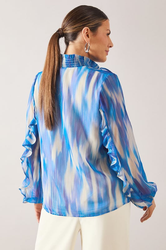 Elegant V-neckline with delicate ruffle detailing along the front
        Flowing long sleeves with gathered cuffs for a feminine silhouette
        Practical chest pockets add functionality to this sophisticated design
        Lightweight spun viscose fabric offers comfort and graceful drape
        Striking watercolour-inspired pattern creates visual interest and versatility
    
    This Wallis shirt combines sophistication with everyday wearability. The fluid silhouette and artistic print make it perfect for elevating your daytime wardrobe. Style with wide-leg trousers as shown for a polished look that works beautifully for lunch dates or family gatherings. For casual outings, pair with your favourite denim and flat sandals. The versatile design transitions effortlessly from office to weekend, simply by changing your accessories. Add statement earrings and a delicate necklace to draw attention to the flattering V-neckline. The ruffle detailing adds a touch of glamour whilst maintaining the shirt's comfortable, relaxed feel - ideal for the woman who appreciates both style and practicality in her wardrobe essentials.