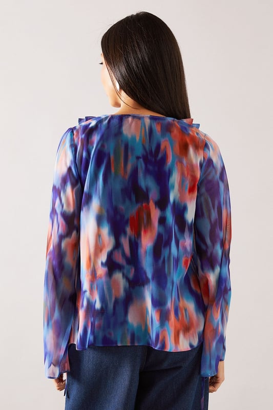 Elegant V-neckline with cascading ruffle detail for a feminine touch
        Flowing long sleeves with delicate tie cuffs for adjustable styling
        Lightweight, floaty fabric that drapes beautifully across the silhouette
        Versatile regular fit that flatters all body shapes
        Distinctive watercolour-inspired print that adds visual interest to any outfit
    
    This Wallis blouse combines sophisticated style with everyday comfort. The eye-catching ruffle detail creates a flattering vertical line while the tie feature adds a touch of refinement. Perfect for daytime occasions, style with wide-leg denim trousers and a statement belt for family gatherings or weekend brunches. The flowing sleeves create movement and balance the silhouette beautifully. For a more casual approach, pair with your favourite jeans and flat sandals for shopping trips or coffee dates. The versatile design transitions effortlessly from desk to dinner - simply swap your daytime accessories for more striking jewellery to refresh your look. This blouse offers the glamour and sophistication Wallis is known for whilst maintaining comfort for all-day wear.