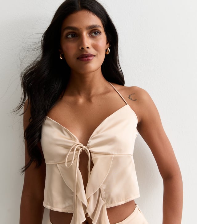 Indulge in luxury with our Champagne Satin Ruffle Tie Front Top. The smooth and lustrous satin fabric drapes elegantly and the ruffle and tie front details add a touch of sophistication. Perfect for any occasion, this top will make you feel glamorous and exclusive.