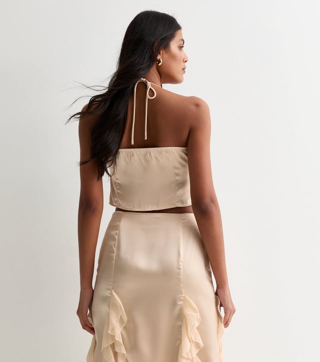 Indulge in luxury with our Champagne Satin Ruffle Tie Front Top. The smooth and lustrous satin fabric drapes elegantly and the ruffle and tie front details add a touch of sophistication. Perfect for any occasion, this top will make you feel glamorous and exclusive.