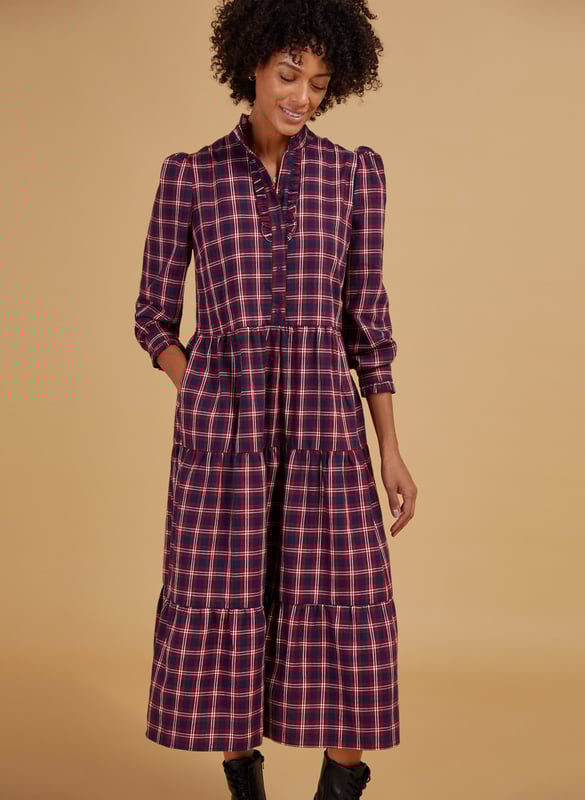 Description\nFits true to size, we suggest ordering your normal size.\nA relaxed checked dress with sleeves makes weekend dressing simple - whatever the weather is doing. The Cara’s ruffled collar and frilly placket and cuffs lend a feminine twist to a masculine pattern, and is so easy to throw-on with trainers or boots. The top half buttons down to the waist and there’s lots of volume in the sleeves - when the temperature really dips, layer in a slim-fitting rollneck for maximum wear.\n\nMade from yarn-dyed organic cotton\nLoose tiered skirt\nPockets in side seams\nRelaxed fit\n\n\nSustainable Attributes:\n  Made in Europe   Low Impact   Natural fibres    Organic   Ethically made    Low Carbon   Vegan \n\nDetails\n100% Organic Cotton Delicate Machine Wash - 40°Product code: DR40473-RCKBack shoulder at neck to hem - 124cm (48 7/8)Sleeve length - 64.5cm (25 3/8)