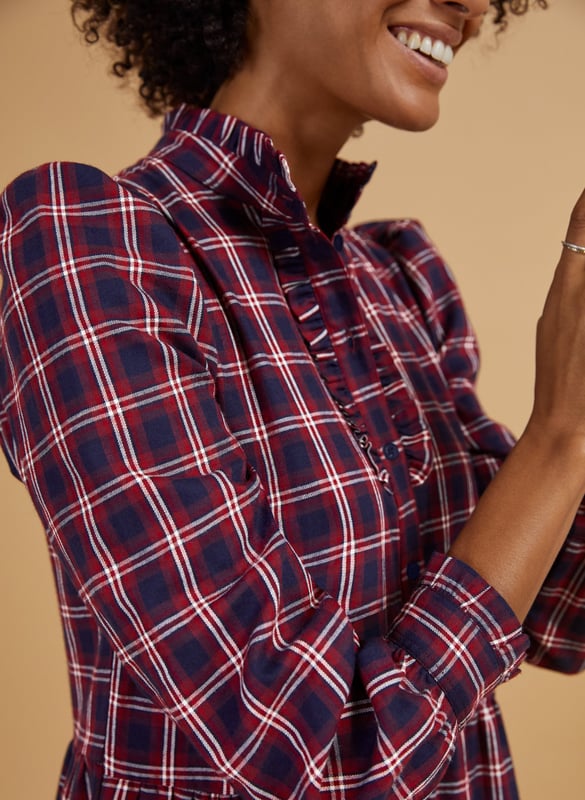 Description\nFits true to size, we suggest ordering your normal size.\nA relaxed checked dress with sleeves makes weekend dressing simple - whatever the weather is doing. The Cara’s ruffled collar and frilly placket and cuffs lend a feminine twist to a masculine pattern, and is so easy to throw-on with trainers or boots. The top half buttons down to the waist and there’s lots of volume in the sleeves - when the temperature really dips, layer in a slim-fitting rollneck for maximum wear.\n\nMade from yarn-dyed organic cotton\nLoose tiered skirt\nPockets in side seams\nRelaxed fit\n\n\nSustainable Attributes:\n  Made in Europe   Low Impact   Natural fibres    Organic   Ethically made    Low Carbon   Vegan \n\nDetails\n100% Organic Cotton Delicate Machine Wash - 40°Product code: DR40473-RCKBack shoulder at neck to hem - 124cm (48 7/8)Sleeve length - 64.5cm (25 3/8)