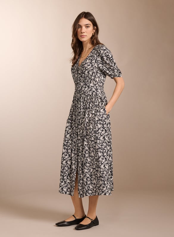 Description\nIf you love tea dresses then you’ll love Holly. This contemporary take in swishy crepe features a black and white ditsy print which goes effortlessly with denim and leather biker jackets. It has a flat waistband panel to the front and is smocked at the back for all-day comfort. With gathering around the shoulders, it’s a pretty midi dress to pair with ballet pumps or loafers.\n\nMade in Europe\nCrafted in LENZING™ ECOVERO™ crepe\nButtons through to the knee with rouleau loop fastenings\nElbow-length sleeves\nPockets in side seams\n\n\nSustainable Attributes:\n Low Water Use Ethically made  Vegan  \n\nDetails\nModel is 5'10 (177cm) and is wearing a UK 10100% LENZING™ ECOVERO™ ViscoseDelicate Machine Wash - 30°Product code: DR40569-BDTBack shoulder at neck to hem - 122cm (48)Sleeve length - 32.5cm (12 5/8)