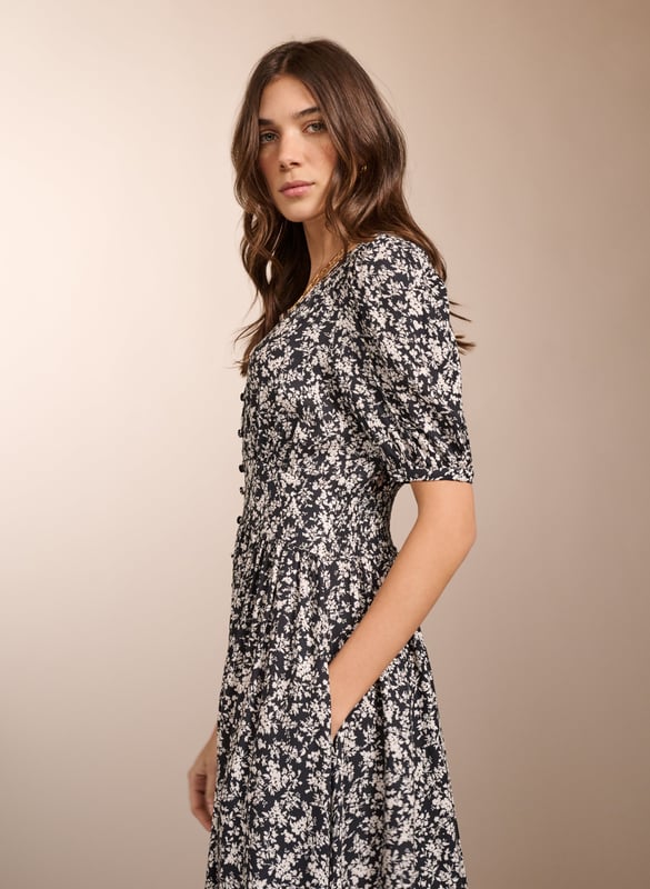 Description\nIf you love tea dresses then you’ll love Holly. This contemporary take in swishy crepe features a black and white ditsy print which goes effortlessly with denim and leather biker jackets. It has a flat waistband panel to the front and is smocked at the back for all-day comfort. With gathering around the shoulders, it’s a pretty midi dress to pair with ballet pumps or loafers.\n\nMade in Europe\nCrafted in LENZING™ ECOVERO™ crepe\nButtons through to the knee with rouleau loop fastenings\nElbow-length sleeves\nPockets in side seams\n\n\nSustainable Attributes:\n Low Water Use Ethically made  Vegan  \n\nDetails\nModel is 5'10 (177cm) and is wearing a UK 10100% LENZING™ ECOVERO™ ViscoseDelicate Machine Wash - 30°Product code: DR40569-BDTBack shoulder at neck to hem - 122cm (48)Sleeve length - 32.5cm (12 5/8)