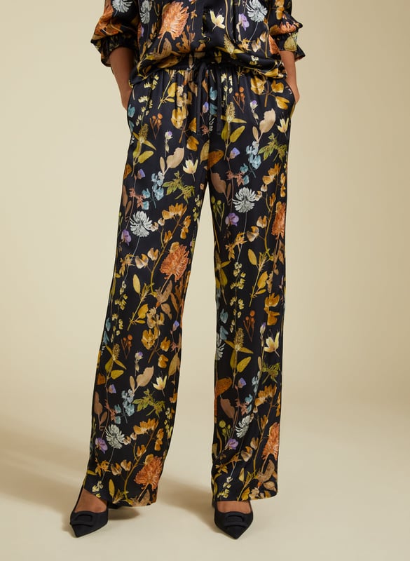 Description\nFits true to size, we suggest ordering your usual size.\nInject a little fun into your trouser collection with the Mandy Satin Trousers. This style boasts a beautiful botanical print on a black base, lending interest to crisp white blouses and oversize tees. But our favourite way to style them is with the matching Jasmine Satin Blouse for a considered co-ord. Cut for a wide-leg, pyjama-style silhouette, they are the ultimate spring-in-your-step piece.\n\nMade in Europe\nCrafted in a recycled satin blend\nElasticated waist with draw-cord\nSide slash pockets and back patch pockets\nWide-leg, relaxed fit\nBlack piping detail down each leg\nMatching shirt available\n\n\nSustainable Attributes:\n  Low Impact   Low Water Use  Ethically made  Low Carbon  \n\nDetails\nModel is 5'10 (177cm) and is wearing a UK 1049% Lenzing™ EcoVero™ Viscose, 51% Recycled ViscoseDelicate Machine Wash - 30°Product code: TR40313-BTOInside leg - 77.5cm (30 1/2)