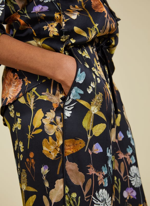 Description\nFits true to size, we suggest ordering your usual size.\nInject a little fun into your trouser collection with the Mandy Satin Trousers. This style boasts a beautiful botanical print on a black base, lending interest to crisp white blouses and oversize tees. But our favourite way to style them is with the matching Jasmine Satin Blouse for a considered co-ord. Cut for a wide-leg, pyjama-style silhouette, they are the ultimate spring-in-your-step piece.\n\nMade in Europe\nCrafted in a recycled satin blend\nElasticated waist with draw-cord\nSide slash pockets and back patch pockets\nWide-leg, relaxed fit\nBlack piping detail down each leg\nMatching shirt available\n\n\nSustainable Attributes:\n  Low Impact   Low Water Use  Ethically made  Low Carbon  \n\nDetails\nModel is 5'10 (177cm) and is wearing a UK 1049% Lenzing™ EcoVero™ Viscose, 51% Recycled ViscoseDelicate Machine Wash - 30°Product code: TR40313-BTOInside leg - 77.5cm (30 1/2)
