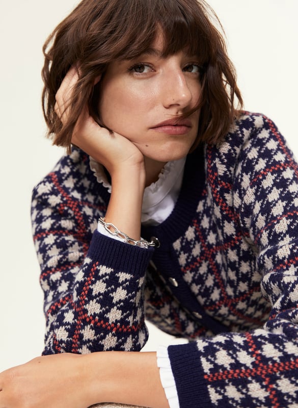 Description\nFits true to size, we suggest ordering your normal size.\nIs the Prudence a jacket or a cardigan? That’s your call, depending on how you style it! Wear it on its own with a mini skirt, or over a ruffle-collar blouse with jeans - the potential is limitless. Its classic houndstooth pattern in navy blue and beige is offset with an orange for a contemporary pop of colour.\nInspired by a family heirloom, Prudence is designed to give a little texture and joy to any outfit. Wear as a jacket or cardigan. I love how versatile it is. - Natalie, Design Director\n\nCrafted in a recycled wool blend\nBoxy fit\nFaux pockets\nSilver buttons\n\n\nSustainable Attributes:\n Made in Europe  Low Water Use   Mulesing free   Recycled Fibres  Ethically made   Raw Material Traced \n\nDetails\nModel is 5'10 (177cm) and is wearing a UK 1045% Merino Wool, 35% GRS Recycled Wool, 20% GRS Recycled NylonHand Wash Or Dry Clean OnlyProduct Code: KW40252-NANBack shoulder at neck to hem - 55cm (21 3/4)Sleeve length - 60cm (23 5/8)