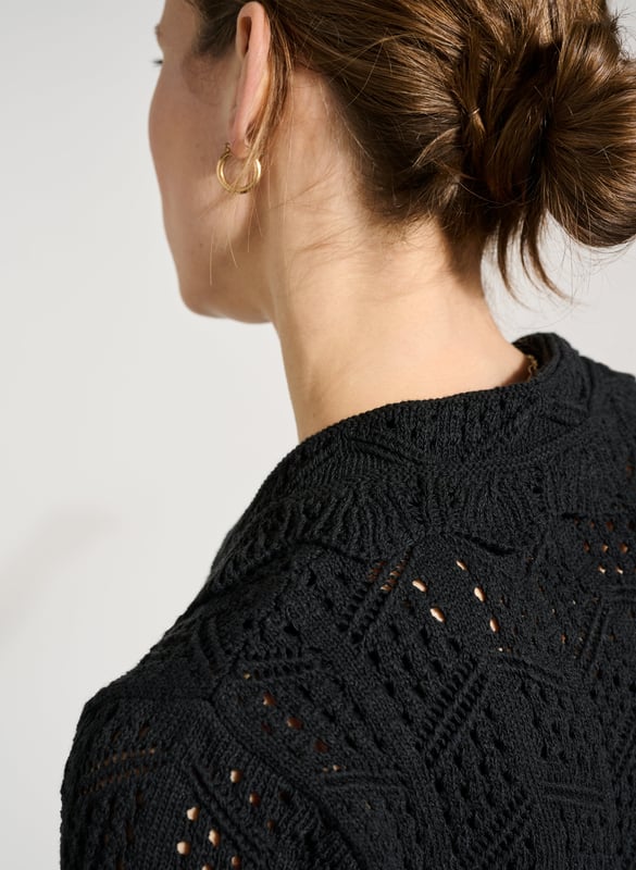 Description\nFits true to size, we suggest ordering your usual size.\nWe’re so in love with Pearl that we’ll be wearing it at every given opportunity! Either as a light cover-up over a  or as a top with a vest underneath. This crochet-style cardigan is cut for a short, boxy fit, and adorned with scallop edges around the collar hem. Best of all, it’s made from ECOTEC®, a recycled yarn with a low carbon footprint.\n\nMade in Europe\nCrafted in ECOTEC®\nOpenwork knit detail\nButtons down\nLoose, elbow-length sleeves\n\n\nSustainable Attributes:\n  Low Impact   Low Water Use  Recycled Fibres   Ethically made  Vegan   Low Carbon \n\nDetails\nModel is 5'10 (177cm) and is wearing a UK 1075% ECOTEC® Cotton, 20% ECOTEC® Polyester, 5% Other fibresHand Wash or Dry Clean OnlyProduct Code: KW40283-BLKCentre back waist to hem - 48cm (18 7/8)Sleeve length - 30cm (11 7/8)