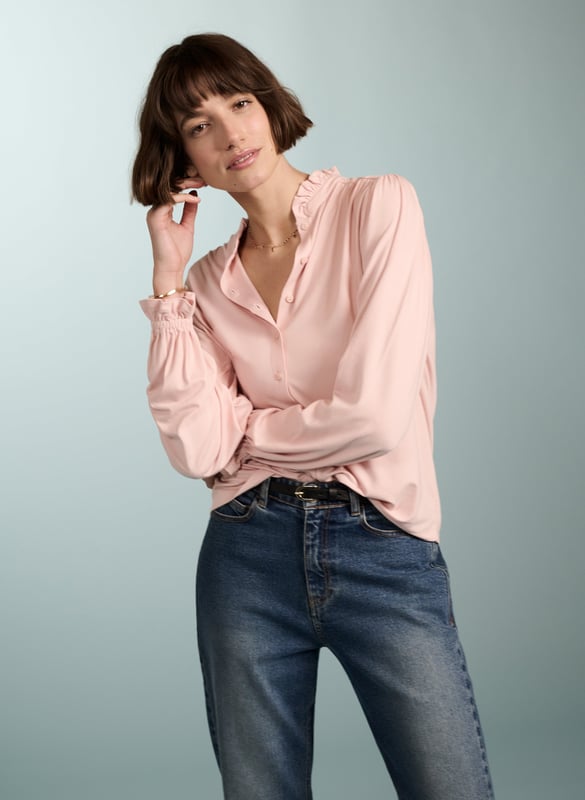 Description\nFits true to size, we suggest ordering your usual size.\nSima is a frill-adorned take on our best-selling Imken blouse. This feminine shirt features a relaxed collar with a ruffled trim - a detail that’s echoed in the elasticated cuffs. Cut from planet-conscious jersey for easy, all-day comfort, it’s a hard-working style to see you through work days and weekends.\n\nMade in Europe\nCrafted in LENZING™ ECOVERO™ jersey\nRelaxed fit\nGathered detail around the shoulders\n\n\nSustainable Attributes:\n Low Impact  Low Water Use Ethically made  Vegan   Low Carbon  \n\nDetails\nModel is 5'10 (177cm) and is wearing a UK 1095% LENZING™ ECOVERO™ Viscose, 5% ElastaneDelicate Machine Wash 30˚Product code: JB40007-PPKBack shoulder at neck to hem - 62cm (24 2/5)Sleeve length - 62cm (24 2/5)