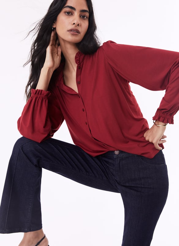 Description\nFits true to size, however if you are inbetween sizes, we suggest you size down.\nSima is a frill-adorned take on our best-selling Imken blouse. This feminine shirt features a relaxed collar with a ruffled trim - a detail that’s echoed in the elasticated cuffs. Cut from planet-conscious jersey for easy, all-day comfort, it’s a hard-working style to see you through work days and weekends.\nLove Sima for wearing solo or under knits - Baukjen\n\nMade in Europe\nCrafted in LENZING™ ECOVERO™ jersey\nRelaxed fit\nGathered detail around the shoulders\n\n\nSustainable Attributes:\n\n  \n Low Impact \n\n Low Water Use \n  \n Natural fibres \n   Ethically made\n\n Low Carbon \n\nDetails\n95% LENZING™ ECOVERO™ Viscose, 5% ElastaneDelicate Machine Wash - 30°Product code: JB40007-PWHBack shoulder at neck to hem - 62cm (24 2/5)Sleeve length - 62cm (24 2/5)