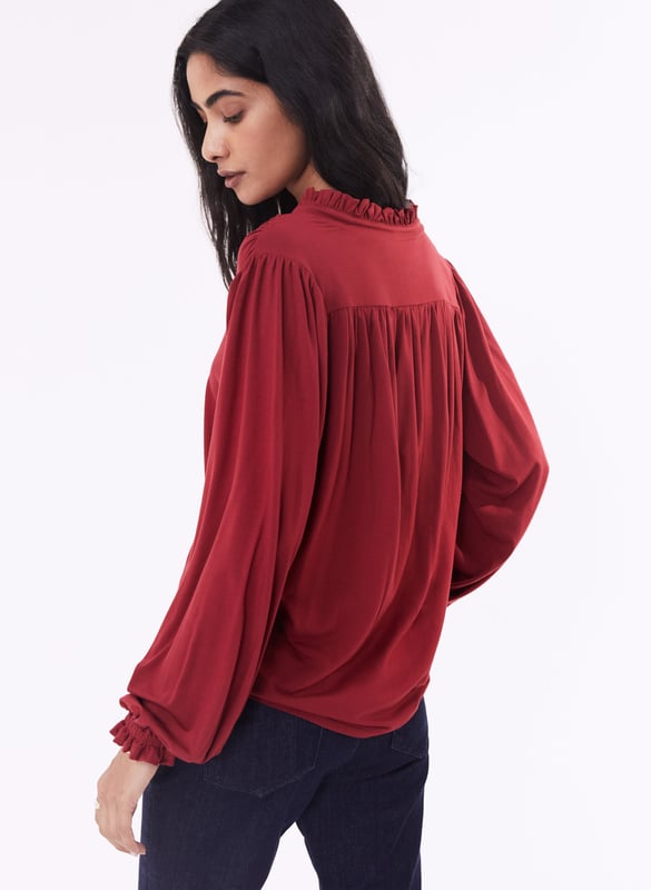 Description\nFits true to size, however if you are inbetween sizes, we suggest you size down.\nSima is a frill-adorned take on our best-selling Imken blouse. This feminine shirt features a relaxed collar with a ruffled trim - a detail that’s echoed in the elasticated cuffs. Cut from planet-conscious jersey for easy, all-day comfort, it’s a hard-working style to see you through work days and weekends.\nLove Sima for wearing solo or under knits - Baukjen\n\nMade in Europe\nCrafted in LENZING™ ECOVERO™ jersey\nRelaxed fit\nGathered detail around the shoulders\n\n\nSustainable Attributes:\n\n  \n Low Impact \n\n Low Water Use \n  \n Natural fibres \n   Ethically made\n\n Low Carbon \n\nDetails\n95% LENZING™ ECOVERO™ Viscose, 5% ElastaneDelicate Machine Wash - 30°Product code: JB40007-PWHBack shoulder at neck to hem - 62cm (24 2/5)Sleeve length - 62cm (24 2/5)