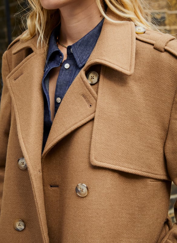 Description\nFits true to size, we suggest ordering your usual size.\nThe Ingrid Belted Trench Coat is a buy-now, wear-it-forever sort of wardrobe staple. Crafted in a heavy, recycled twill wool blend, it takes all its styling cues from the classic trench coat. Expect a double-breasted silhouette, epaulettes, storm flap and a belt. Beautifully cut and fully lined, it will elegantly elevate any outfit while offering maximum warmth. Whether it’s for weekdays or weekends, Ingrid can do it all. \n\nMade in Europe \nCrafted in a premium recycled wool blend \nTabs on cuffs \nFull length \nWelt pockets \n\n\nSustainable Attributes:\n\n\n Low Impact \n\n Low Water Use \n\n Mulesing free \n\n Natural fibres \n\n Recycled Fibres \n\n Ethically made \n\n\nDetails\nModel is 5'10 (177cm) and is wearing a UK 10\n65% Recycled Wool, 30% Recycled Polyester, 5% Other Fibres\nDry CLean Only\nProduct Code: OT40103-TAU \nBack shoulder at neck to hem - 120cm (47 1/4)\nSleeve length - 60cm (23 5/8)