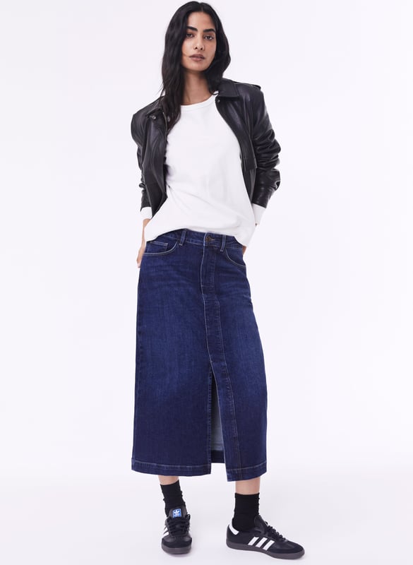 Description\nFits true to size, we suggest ordering your usual size.\nThe hot-ticket item right now according to our Design Director Natalie. A long-line denim skirt. In organic cotton of course. Emilia is a cool alternative to jeans, with a split up the front for a flash of leg and easy movement. It’s a versatile piece which hugs the waist and hips before tapering out into a chic column shape. So versatile, you can dress it up with loafers and a shirt, or down with a sweater and sneakers.\n\nCrafted in organic cotton denim\nLong midi length\nFront split detail\nZip button and fly fastening\nClassic jeans pockets\n\n\nSustainable Attributes:\n  Made in Europe    Natural fibres    Organic    Ethically made    Vegan    Low Carbon    Raw Material Traced \n\nDetails\nModel is 5'10 (177cm) and is wearing a UK 1099% Organic Cotton, 1% ElastaneDelicate Machine Wash - 30°Product code: SK40163-DIN Centre back waist to hem - 81cm (31 7/8)