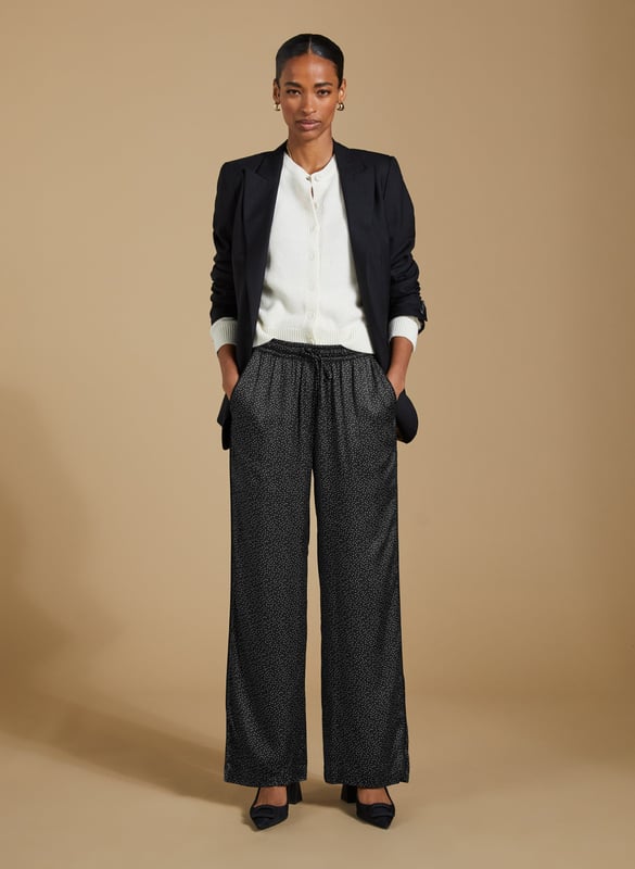 Description\nFits true to size, we suggest ordering your usual size.\nAdd a playful twist to your wardrobe with the Mandy Satin Trousers. Featuring a chic black mini spot print on a satin finish, these wide-leg trousers are perfect for pairing with crisp white blouses or oversized tees. But our favourite way to style them is with the matching Saffron Satin Blouse for a chic, coordinated look. Cut in a wide-leg, pyjama-style silhouette, these trousers are perfect for bringing a bit of effortless elegance to your day.\n\nMade in Europe\nCrafted in a recycled satin blend\nElasticated waist with draw-cord\nSide slash pockets and back patch pockets\nWide-leg, relaxed fit\nBlack piping detail down each leg\nMatching shirt available\n\n\nSustainable Attributes:\n  Low impact  Low Water Use   Natural fibres   Recycled Fibres   Ethically made  Low Carbon \n\nDetails\nModel is 5'10 (177cm) and is wearing a UK 1049% Lenzing™ EcoVero™ Viscose, 51% Recycled ViscoseDelicate Machine Wash 30˚Wash Inside Out - Wash Dark Colours SeparatelyProduct Code: TR40313-BNSInside leg - 77.5cm (30 1/2)