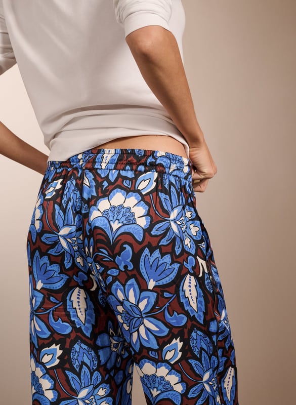 Description\nA building blend of pattern and colour, the Mandy are surprisingly versatile. Guaranteed to lend a touch of fun to casual tees, they look chic with a crisp white blouse. But our favourite way to style them is with the matching Gloria blouse for a fun and fearless outfit. Cut as a wide-leg, they are the ultimate spring-in-your-step piece. Enjoy for years. \n\nMade in Europe\nCrafted from a recycled satin blend \nElasticated waist with draw-cord \nSide slash pockets  \nWide-leg, relaxed fit \nBlack piping detail down each leg \nMatching top available \n\n\nSustainable Attributes:\n \n\n Low impact \n\n Low Water Use\n \n Recycled Fibres \n\n Ethically made\n\n Vegan \n\n\n\nDetails\n Model is 5'10 (177cm) and is wearing a UK 10\n49% LENZING™ ECOVERO™ Viscose, 51% Recycled Viscose\nDelicate Machine Wash 30˚\nProduct code: TR40313-BFA\nInside leg - 77cm (30 1/4)