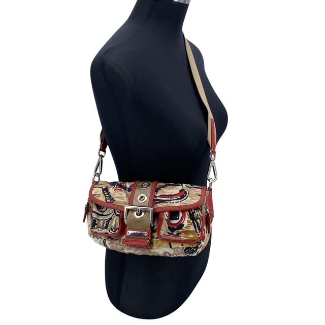 Empfohlener Verkaufspreis
Erleben Sie die perfekte Balance aus modernem Stil und funktionalem Design mit der PRADA Tessuto- und Leder-Schultertasche mit Schnalle und wunderschönem „Venice“-Print. Die „Venice Watercolor“-Kollektion von Prada ist eine unverwechselbare Linie, die mit ihrem künstlerischen Design die Essenz Venedigs einfängt. Diese Tasche mit ihrem modernen, kantigen Look besteht aus beige-rotem „Tessuto“-Nylon-Canvas, wunderschön kombiniert mit roten Lederakzenten, die einen raffinierten und zugleich markanten Look verleihen. Die obere Klappe, gesichert durch einen stilvollen Riemen mit Schnallendetail, verleiht einen Hauch robuster Eleganz, während der Magnetknopfverschluss Ihre Wertsachen sicher verstaut. Mit zwei Reißverschlusstaschen vorne für einfachen Zugriff auf kleinere Utensilien verbindet die Tasche Funktionalität mit High Fashion. Im Inneren präsentiert sich das charakteristische PRADA-Futter und eine seitliche Reißverschlusstasche für zusätzliche Ordnung. Das ikonische PRADA-Dreieckslogo an der Seite und das „PRADA – Made in Italy“-Etikett im Inneren erinnern an die Tradition der Marke für Luxus und hochwertige Handwerkskunst. Ein verstellbarer Schultergurt ermöglicht eine individuelle Passform und macht diese Tasche so vielseitig wie stilvoll. Ob Sie einen lässigen Tagesausflug oder eine schicke Abendveranstaltung planen, die PRADA Tessuto Venice Buckle Shoulder Bag bietet die perfekte Mischung aus Stil und Eleganz. Zustandsbewertung: A - AUSGEZEICHNET. Zustandsdetails: Wenig getragen. Bitte prüfen Sie sorgfältig und fragen Sie nach, wenn Sie weitere Details benötigen oder Fragen haben. Maße (cm): Tiefe: 6,4 Höhe: 14,0 Länge: 24,1 Weitere Details: Staubbeutel? Nein Schlüssel? Nein Box? Nein Maße: Breite: 64 mm Länge: 241 mm Höhe: 140 mm