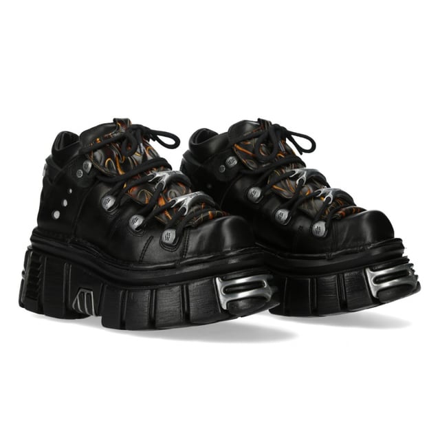 New Rock M-106N-C86 Zwarte Vlammen Leren Gothic Enkel Plateau Laarzen Ontketen een vurige attitude met de New Rock M-106N-C86 enkellaarsjes uit de Metallic Collection. Deze op maat gemaakte laarzen combineren gothic en punk esthetiek met de kenmerkende metallic kracht van New Rock en zijn voorzien van opvallende vlamaccenten op echt rundleer. De hoge platformzool, gecombineerd met een hak van 8 cm en een platform van 6 cm, zorgt voor een dramatische hoogte en een krachtige uitstraling. Met de klassieke vetersluiting en een compacte schacht van 10 cm is deze unisex stijl gemaakt voor onverschrokken expressie. Belangrijkste kenmerken: Materiaal (buitenkant): Rundleer Materiaal (binnenkant): Synthetisch Hakhoogte: 8 cm Platformhoogte: 6 cm Zoolmateriaal: PU Ultra Sluiting: Veters (koord) Schachthoogte: 10 cm Stijl: Gothic, Heavy, Punk, Rock Ontwerp: Unisex (geschikt voor alle geslachten)