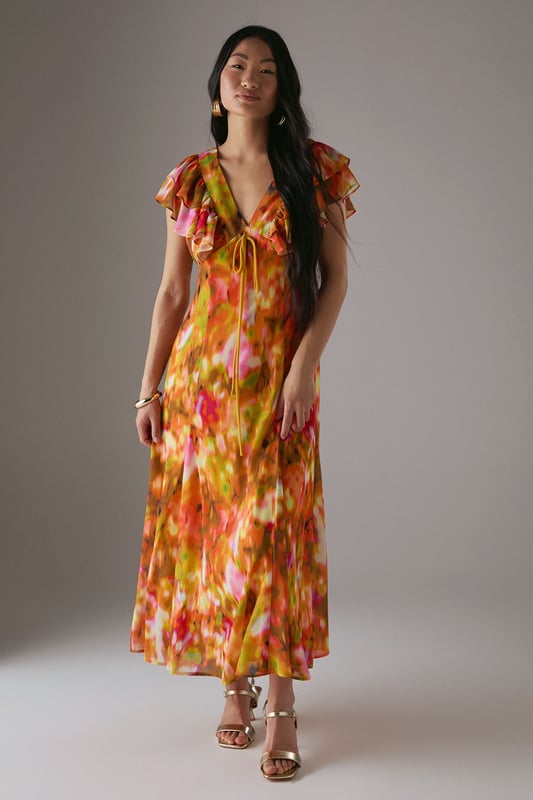 Feminine V-neckline with delicate tie-front detail for adjustable styling
        Romantic flutter sleeves with frilled edges adding movement and dimension
        Flowing midi length tea dress silhouette that flatters the figure
        Vibrant floral print pattern perfect for seasonal daywear
        Lightweight woven fabric with gentle drape for all-day comfort
    
    This captivating Warehouse tea dress combines effortless femininity with contemporary flair. The flattering V-neckline features a charming tie-front detail that allows for customised styling, while the delicate flutter sleeves with frilled edges create a soft, romantic silhouette. The flowing midi length offers versatile wear - pair with strappy sandals as seen on our model for casual brunches or garden parties, or dress down with white trainers for weekend shopping trips. The vibrant floral pattern makes this piece a standout addition to your daytime wardrobe. Perfect for family gatherings or casual meet-ups with friends, this dress transitions beautifully from spring through summer. Layer with a denim jacket and ankle boots during cooler months for extended seasonal wear.
