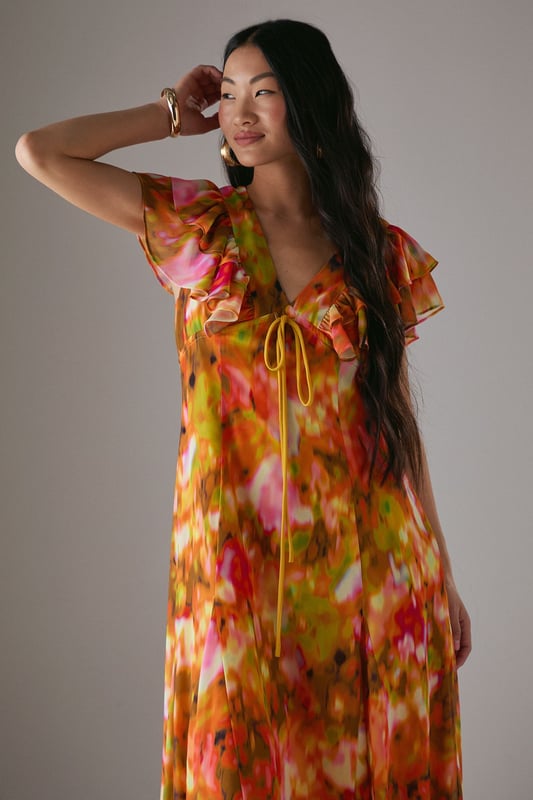 Feminine V-neckline with delicate tie-front detail for adjustable styling
        Romantic flutter sleeves with frilled edges adding movement and dimension
        Flowing midi length tea dress silhouette that flatters the figure
        Vibrant floral print pattern perfect for seasonal daywear
        Lightweight woven fabric with gentle drape for all-day comfort
    
    This captivating Warehouse tea dress combines effortless femininity with contemporary flair. The flattering V-neckline features a charming tie-front detail that allows for customised styling, while the delicate flutter sleeves with frilled edges create a soft, romantic silhouette. The flowing midi length offers versatile wear - pair with strappy sandals as seen on our model for casual brunches or garden parties, or dress down with white trainers for weekend shopping trips. The vibrant floral pattern makes this piece a standout addition to your daytime wardrobe. Perfect for family gatherings or casual meet-ups with friends, this dress transitions beautifully from spring through summer. Layer with a denim jacket and ankle boots during cooler months for extended seasonal wear.