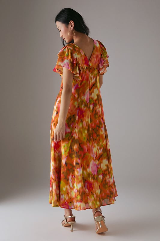 Feminine V-neckline with delicate tie-front detail for adjustable styling
        Romantic flutter sleeves with frilled edges adding movement and dimension
        Flowing midi length tea dress silhouette that flatters the figure
        Vibrant floral print pattern perfect for seasonal daywear
        Lightweight woven fabric with gentle drape for all-day comfort
    
    This captivating Warehouse tea dress combines effortless femininity with contemporary flair. The flattering V-neckline features a charming tie-front detail that allows for customised styling, while the delicate flutter sleeves with frilled edges create a soft, romantic silhouette. The flowing midi length offers versatile wear - pair with strappy sandals as seen on our model for casual brunches or garden parties, or dress down with white trainers for weekend shopping trips. The vibrant floral pattern makes this piece a standout addition to your daytime wardrobe. Perfect for family gatherings or casual meet-ups with friends, this dress transitions beautifully from spring through summer. Layer with a denim jacket and ankle boots during cooler months for extended seasonal wear.