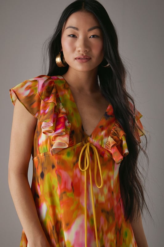 Feminine V-neckline with delicate tie-front detail for adjustable styling
        Romantic flutter sleeves with frilled edges adding movement and dimension
        Flowing midi length tea dress silhouette that flatters the figure
        Vibrant floral print pattern perfect for seasonal daywear
        Lightweight woven fabric with gentle drape for all-day comfort
    
    This captivating Warehouse tea dress combines effortless femininity with contemporary flair. The flattering V-neckline features a charming tie-front detail that allows for customised styling, while the delicate flutter sleeves with frilled edges create a soft, romantic silhouette. The flowing midi length offers versatile wear - pair with strappy sandals as seen on our model for casual brunches or garden parties, or dress down with white trainers for weekend shopping trips. The vibrant floral pattern makes this piece a standout addition to your daytime wardrobe. Perfect for family gatherings or casual meet-ups with friends, this dress transitions beautifully from spring through summer. Layer with a denim jacket and ankle boots during cooler months for extended seasonal wear.