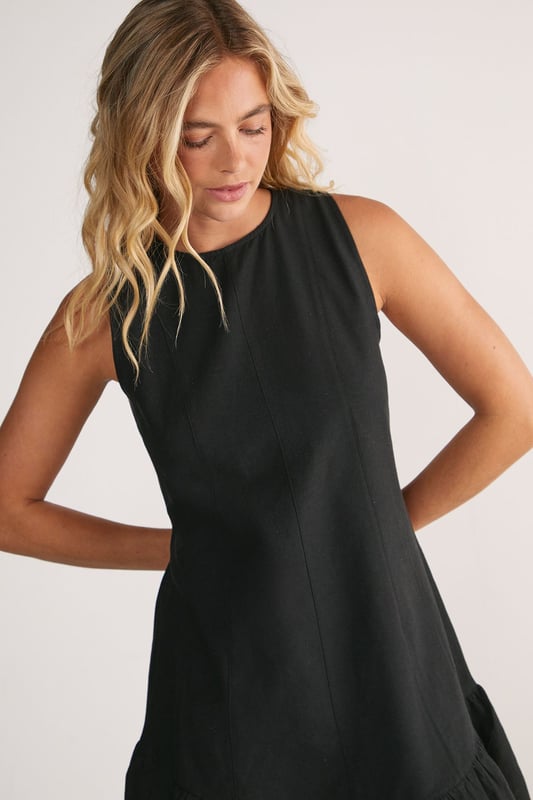 Sleeveless design with high neckline for a sophisticated silhouette
        Vertical seam detailing creates a flattering structured shape
        Playful peplum hem adds movement and feminine flair
        Linen mix fabric offers breathable comfort with natural texture
        Mini length perfect for showcasing legs and statement footwear
    
    This charming mini dress combines simplicity with thoughtful design elements for effortless daytime style. The structured seaming creates a flattering shape that flows into a flirty peplum hem, adding just the right amount of movement as you walk. Style with western boots for a contemporary countryside look, or pair with trainers and an oversized denim jacket for casual weekend brunches. The breathable linen mix fabric makes it ideal for warm-weather gatherings, whilst the versatile high neckline works beautifully with layered necklaces or statement earrings. Perfect for family barbecues, farmers' markets or seaside strolls, this NastyGal dress transitions seamlessly from day to evening with a simple change of accessories.