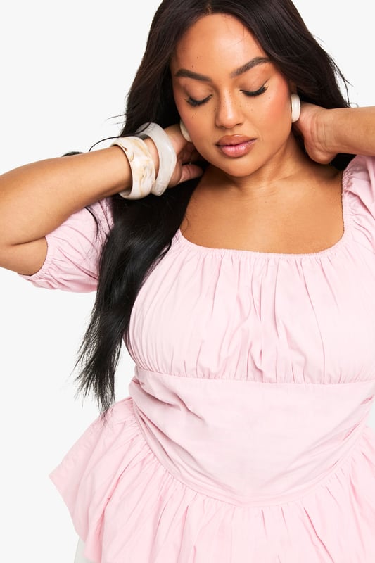 Crafted from breathable cotton poplin for all-day comfort
        Feminine square neckline with delicate gathering detail
        Statement puff sleeves add a romantic touch
        Flattering peplum hem creates a beautiful silhouette
        Designed with inclusive sizing for the perfect plus-size fit
    
    This charming cotton blouse combines contemporary style with classic femininity. The gathered square neckline frames your dcolletage beautifully, while the voluminous puff sleeves create a balanced silhouette that's both on-trend and timelessly elegant. The peplum hem adds definition to your waistline and pairs wonderfully with high-waisted trousers as styled on our model. Perfect for casual daytime events, family gatherings or weekend brunches, this versatile Boohoo blouse can be dressed up with statement earrings and wide-leg trousers for a chic ensemble, or paired with your favourite denim and trainers for a more relaxed look. The lightweight cotton fabric ensures comfort throughout the day, making this a wardrobe essential for the fashion-forward woman who values both style and practicality.