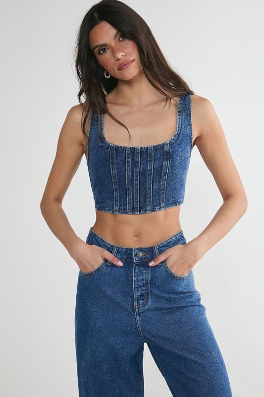 Striking denim corset top with square neckline
        Flattering structured bodice with vertical seam detailing
        Wide shoulder straps for added support and comfort
        Eye-catching lace-up back detail for adjustable fit
        Cropped length perfect for layering or wearing solo
    
    Make a bold statement with this edgy denim corset top from NastyGal. The structured bodice and vertical seaming create a figure-hugging silhouette that flatters your curves, while the square neckline adds a touch of sophistication. The standout feature is the alluring lace-up back, allowing for a customised fit and adding a rebellious flair to your ensemble. Style this versatile piece for casual outings by pairing it with high-waisted wide-leg jeans and trainers for a trendy street-style look. For a night out with friends, team it with a leather mini skirt and ankle boots to amp up the attitude. The cropped length makes it ideal for layering under an oversized blazer or wearing on its own during warmer months. This denim corset top is a must-have addition to any fashion-forward wardrobe, offering endless styling possibilities for various casual occasions.