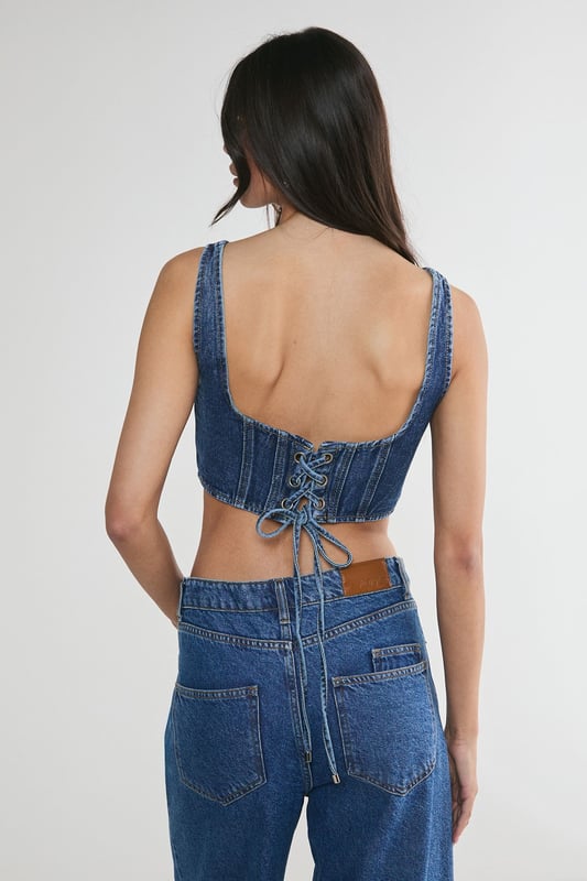Striking denim corset top with square neckline
        Flattering structured bodice with vertical seam detailing
        Wide shoulder straps for added support and comfort
        Eye-catching lace-up back detail for adjustable fit
        Cropped length perfect for layering or wearing solo
    
    Make a bold statement with this edgy denim corset top from NastyGal. The structured bodice and vertical seaming create a figure-hugging silhouette that flatters your curves, while the square neckline adds a touch of sophistication. The standout feature is the alluring lace-up back, allowing for a customised fit and adding a rebellious flair to your ensemble. Style this versatile piece for casual outings by pairing it with high-waisted wide-leg jeans and trainers for a trendy street-style look. For a night out with friends, team it with a leather mini skirt and ankle boots to amp up the attitude. The cropped length makes it ideal for layering under an oversized blazer or wearing on its own during warmer months. This denim corset top is a must-have addition to any fashion-forward wardrobe, offering endless styling possibilities for various casual occasions.
