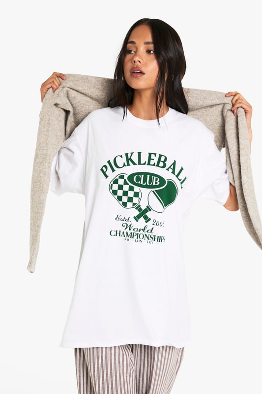 Oversized fit for ultimate comfort and relaxed styling
        Bold Pickleball Club graphic print with retro sports appeal
        Short sleeves with dropped shoulders for a contemporary silhouette
        Soft cotton fabric that's gentle against the skin
        Versatile crew neckline that works with multiple styling options
    
    Make a statement with this trendy oversized Pickleball t-shirt that perfectly balances sporty charm with laid-back cool. The roomy silhouette offers effortless styling potential - pair with striped wide-leg trousers as shown for a contemporary casual look, or team with cycling shorts and trainers for an on-trend athleisure ensemble. Layer under an open shirt or cardigan for cooler days, or simply throw on with your favourite denim and canvas trainers for weekend brunches. This conversation-starting tee works brilliantly for casual gatherings, coffee dates, or relaxed family events. The versatile design allows for customisation with accessories - add a crossbody bag and cap for daytime outings or dress up with statement jewellery and a leather jacket for evening casual wear. A must-have addition to your everyday wardrobe rotation.