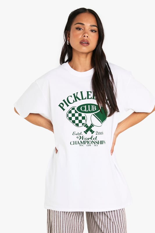 Oversized fit for ultimate comfort and relaxed styling
        Bold Pickleball Club graphic print with retro sports appeal
        Short sleeves with dropped shoulders for a contemporary silhouette
        Soft cotton fabric that's gentle against the skin
        Versatile crew neckline that works with multiple styling options
    
    Make a statement with this trendy oversized Pickleball t-shirt that perfectly balances sporty charm with laid-back cool. The roomy silhouette offers effortless styling potential - pair with striped wide-leg trousers as shown for a contemporary casual look, or team with cycling shorts and trainers for an on-trend athleisure ensemble. Layer under an open shirt or cardigan for cooler days, or simply throw on with your favourite denim and canvas trainers for weekend brunches. This conversation-starting tee works brilliantly for casual gatherings, coffee dates, or relaxed family events. The versatile design allows for customisation with accessories - add a crossbody bag and cap for daytime outings or dress up with statement jewellery and a leather jacket for evening casual wear. A must-have addition to your everyday wardrobe rotation.