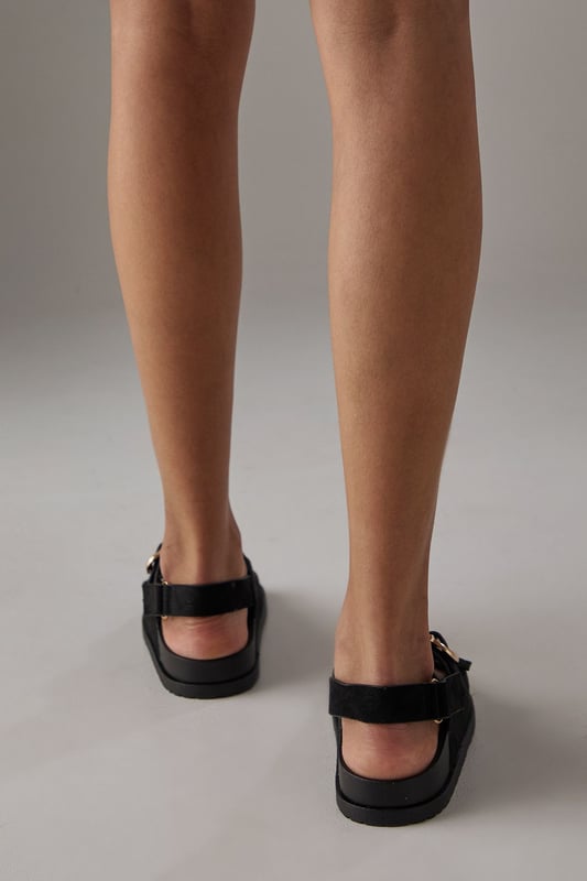 Faux suede slingback sandals featuring distinctive double buckle detailing
        Comfortable footbed design with cushioned insole for all-day wear
        Adjustable slingback strap ensures a secure, customisable fit
        Low heel height of 2.5-4.5cm provides subtle elevation without sacrificing comfort
        Durable synthetic outsole with textured grip for reliable traction
    
    These Reid slingback sandals from Faith blend practicality with contemporary style. The standout double buckle design adds a distinctive touch to these otherwise minimalist footbed sandals, making them a versatile addition to your summer wardrobe. Style them as shown with relaxed trousers and a simple vest top for casual weekend brunches, or pair with a flowing midi dress for garden parties and family gatherings. The adjustable slingback strap ensures these sandals stay securely in place whilst walking, while the cushioned footbed provides essential comfort for long days out. The low heel offers just enough height to flatter without compromising on wearability, making these sandals an ideal choice for city breaks, festival outings or casual summer events where style and comfort are equally important.