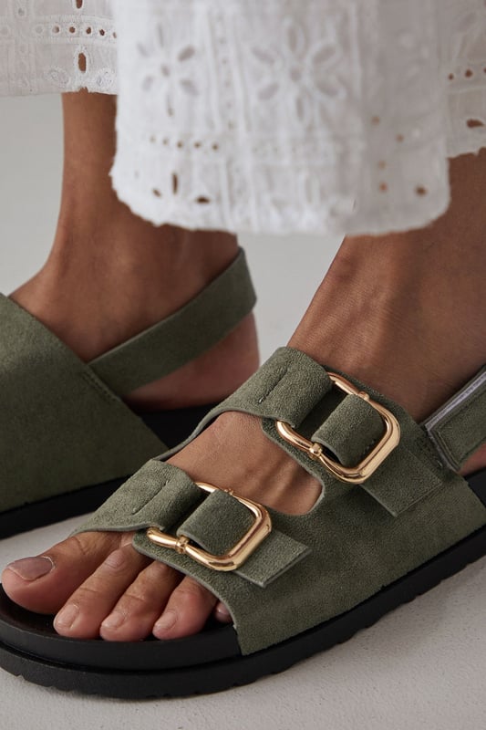 Faux suede slingback sandals featuring distinctive double buckle detailing
        Comfortable footbed design with cushioned insole for all-day wear
        Adjustable slingback strap ensures a secure, customisable fit
        Low heel height of 2.5-4.5cm provides subtle elevation without sacrificing comfort
        Durable synthetic outsole with textured grip for reliable traction
    
    These Reid slingback sandals from Faith blend practicality with contemporary style. The standout double buckle design adds a distinctive touch to these otherwise minimalist footbed sandals, making them a versatile addition to your summer wardrobe. Style them as shown with relaxed trousers and a simple vest top for casual weekend brunches, or pair with a flowing midi dress for garden parties and family gatherings. The adjustable slingback strap ensures these sandals stay securely in place whilst walking, while the cushioned footbed provides essential comfort for long days out. The low heel offers just enough height to flatter without compromising on wearability, making these sandals an ideal choice for city breaks, festival outings or casual summer events where style and comfort are equally important.