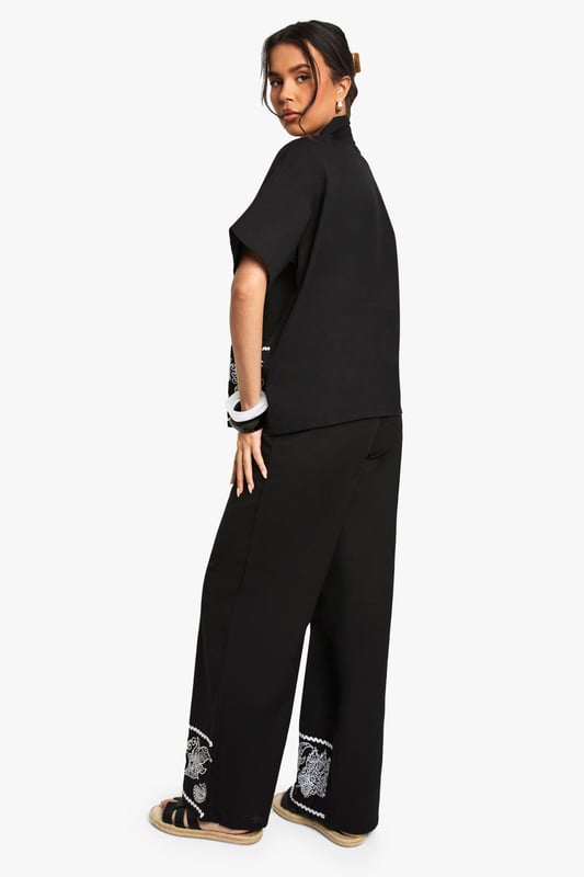 Cotton poplin wide leg trousers featuring striking embroidered border detail
        Relaxed silhouette with comfortable high-rise waistband
        Matching embroidered short-sleeve shirt creates a coordinated set
        Breathable cotton fabric ideal for warm-weather styling
        Versatile wide leg cut that flatters all body shapes
    
    Make a statement in these eye-catching embroidered wide leg trousers from Boohoo. The striking contrast border detailing adds artistic flair to this casual yet sophisticated piece. Crafted from breathable cotton poplin, these trousers offer both comfort and style for your everyday wardrobe. Style them as shown with the matching embroidered shirt for a coordinated look that's perfect for summer gatherings, or pair with a simple vest top and trainers for a more relaxed daytime ensemble. The wide leg silhouette creates a breezy, effortless feel that works brilliantly with flat sandals as pictured. For cooler evenings, layer with a denim jacket and accessorise with a woven bag to complete this contemporary casual look. These trousers transition seamlessly from beach holidays to city breaks, offering versatility for the fashion-forward woman.