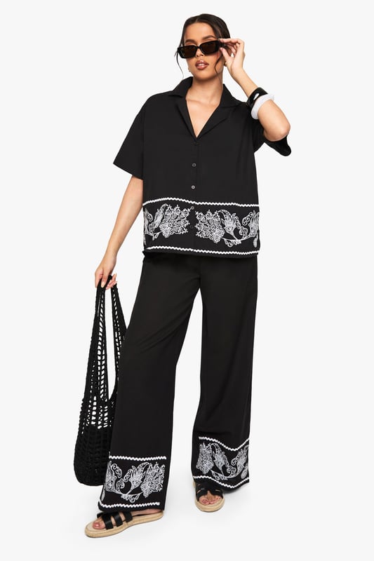 Cotton poplin wide leg trousers featuring striking embroidered border detail
        Relaxed silhouette with comfortable high-rise waistband
        Matching embroidered short-sleeve shirt creates a coordinated set
        Breathable cotton fabric ideal for warm-weather styling
        Versatile wide leg cut that flatters all body shapes
    
    Make a statement in these eye-catching embroidered wide leg trousers from Boohoo. The striking contrast border detailing adds artistic flair to this casual yet sophisticated piece. Crafted from breathable cotton poplin, these trousers offer both comfort and style for your everyday wardrobe. Style them as shown with the matching embroidered shirt for a coordinated look that's perfect for summer gatherings, or pair with a simple vest top and trainers for a more relaxed daytime ensemble. The wide leg silhouette creates a breezy, effortless feel that works brilliantly with flat sandals as pictured. For cooler evenings, layer with a denim jacket and accessorise with a woven bag to complete this contemporary casual look. These trousers transition seamlessly from beach holidays to city breaks, offering versatility for the fashion-forward woman.