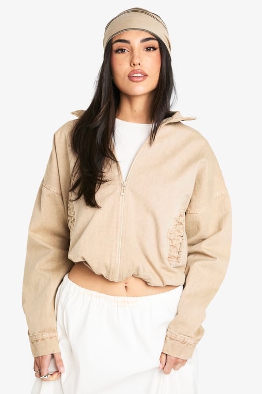 Cropped bomber jacket with a relaxed, oversized fit for effortless styling
        Full front zip closure with ribbed collar, cuffs and hem for a classic bomber silhouette
        Distinctive side pocket detailing with embroidered design elements
        Dropped shoulders and roomy sleeves creating a contemporary, casual shape
        Cotton construction offering breathable comfort for year-round wear
    
    This versatile bomber jacket brings casual cool to your everyday wardrobe. The cropped length pairs beautifully with high-waisted trousers or flowing maxi skirts as shown on our model. For daytime outings, style with a simple white tee, wide-leg trousers and trainers, adding a matching headscarf for a coordinated look. When temperatures drop, layer over a lightweight jumper for added warmth without compromising on style. Perfect for weekend brunches, casual shopping trips or relaxed evening gatherings with friends. The neutral tone makes it an ideal companion piece that works seamlessly with both bold prints and understated basics, allowing you to customise your look for different occasions whilst maintaining that effortlessly chic Boohoo aesthetic.