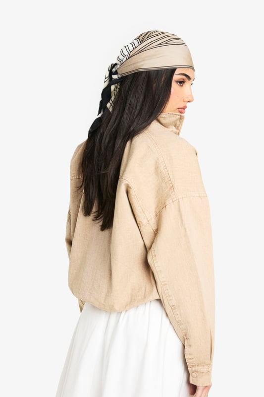 Cropped bomber jacket with a relaxed, oversized fit for effortless styling
        Full front zip closure with ribbed collar, cuffs and hem for a classic bomber silhouette
        Distinctive side pocket detailing with embroidered design elements
        Dropped shoulders and roomy sleeves creating a contemporary, casual shape
        Cotton construction offering breathable comfort for year-round wear
    
    This versatile bomber jacket brings casual cool to your everyday wardrobe. The cropped length pairs beautifully with high-waisted trousers or flowing maxi skirts as shown on our model. For daytime outings, style with a simple white tee, wide-leg trousers and trainers, adding a matching headscarf for a coordinated look. When temperatures drop, layer over a lightweight jumper for added warmth without compromising on style. Perfect for weekend brunches, casual shopping trips or relaxed evening gatherings with friends. The neutral tone makes it an ideal companion piece that works seamlessly with both bold prints and understated basics, allowing you to customise your look for different occasions whilst maintaining that effortlessly chic Boohoo aesthetic.